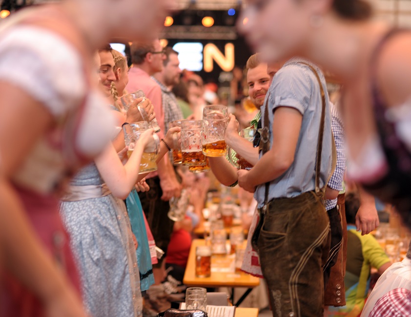 Nachaufnahme von Besuchern, die auf Bierbänken stehen und feiern. Aufnahme ist vorne in einer Unschärfe aufgenommen.